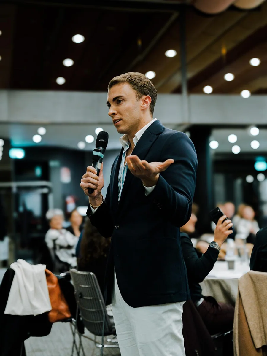 Emanuel Lacitignola parla al microfono davanti alla platea seduta ai tavoli